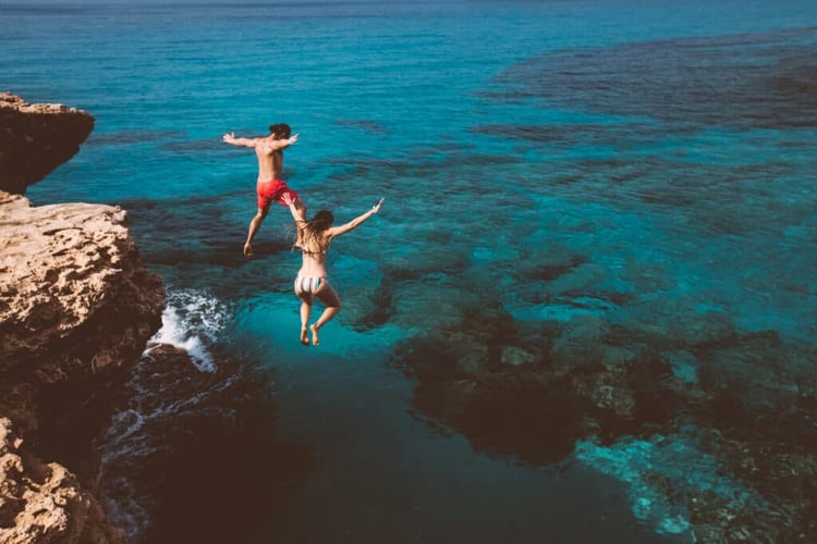 man and women jumping into the sea